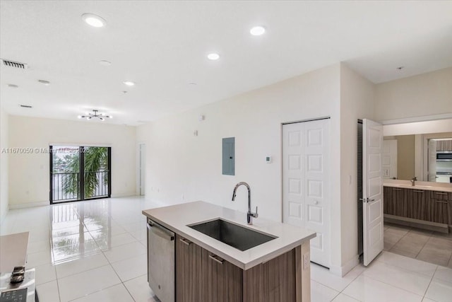 kitchen featuring electric panel, a center island with sink, sink, light tile patterned flooring, and stainless steel appliances