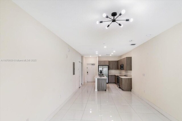 kitchen with a kitchen island, light tile patterned floors, appliances with stainless steel finishes, and a chandelier