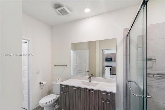 bathroom with toilet, an enclosed shower, and vanity