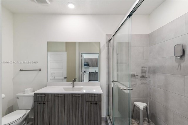 bathroom with vanity, toilet, and a shower with shower door