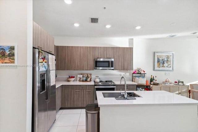 kitchen with light tile patterned floors, an island with sink, stainless steel appliances, and sink