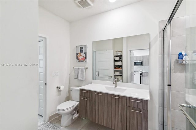 bathroom with tile patterned floors, vanity, an enclosed shower, and toilet