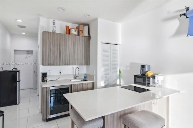 kitchen with sink, wine cooler, a breakfast bar, light tile patterned floors, and black appliances