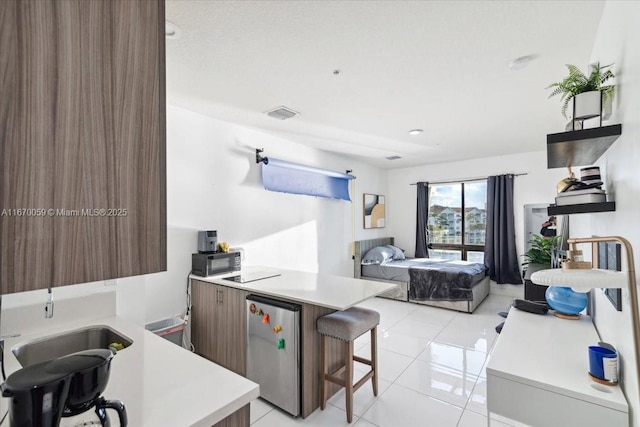 kitchen featuring refrigerator, a kitchen bar, kitchen peninsula, and light tile patterned flooring