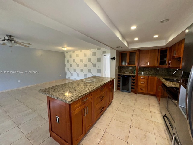 kitchen featuring backsplash, dark stone counters, beverage cooler, ceiling fan, and sink