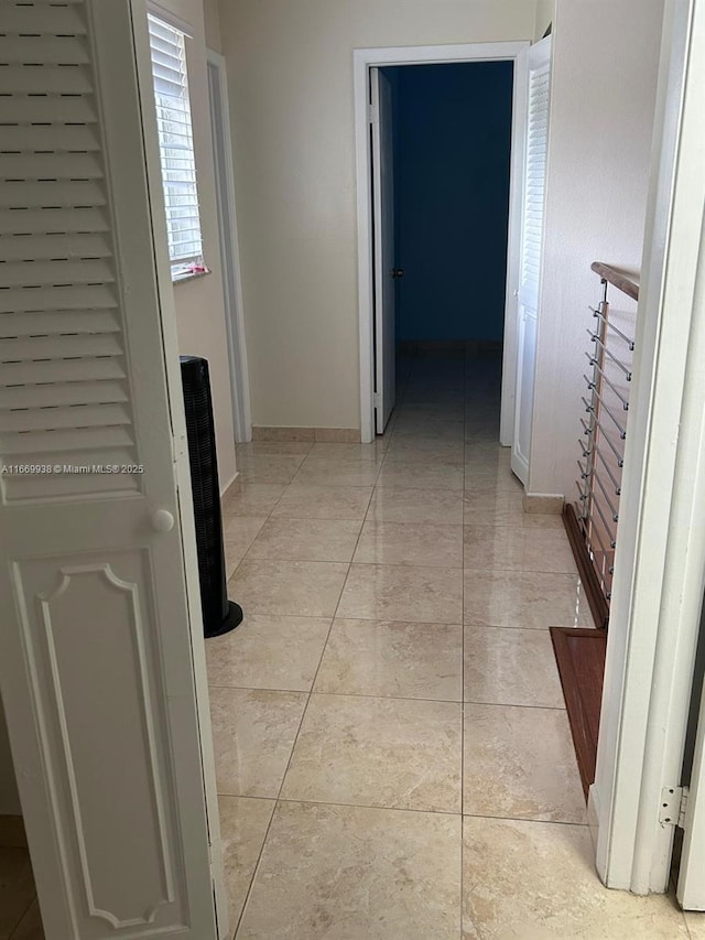 hallway featuring baseboards and light tile patterned flooring