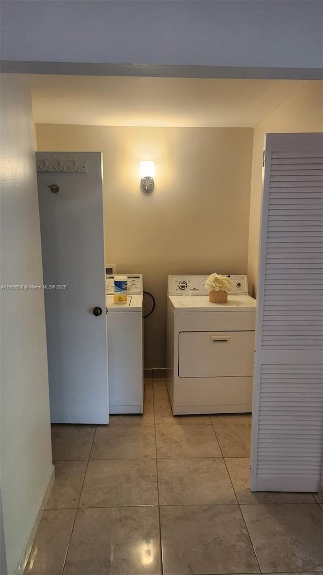 laundry area featuring baseboards, washing machine and dryer, laundry area, and light tile patterned floors