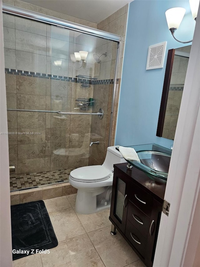 bathroom with tile patterned floors, vanity, toilet, and a shower with shower door