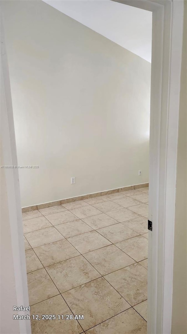 spare room featuring light tile patterned floors and baseboards