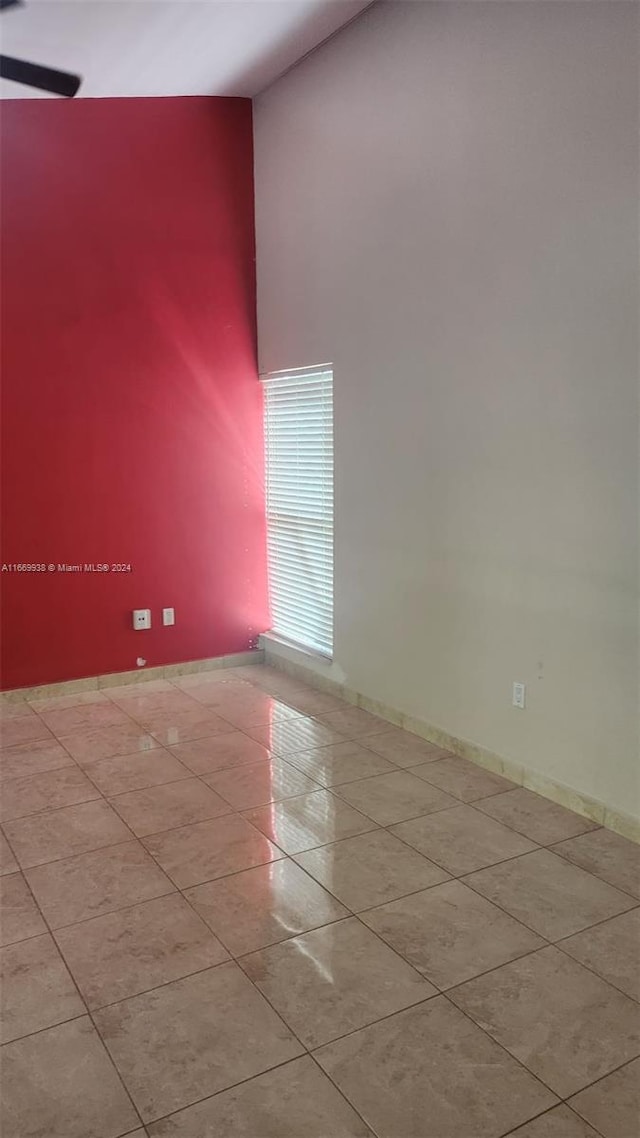 unfurnished room featuring light tile patterned flooring and a towering ceiling