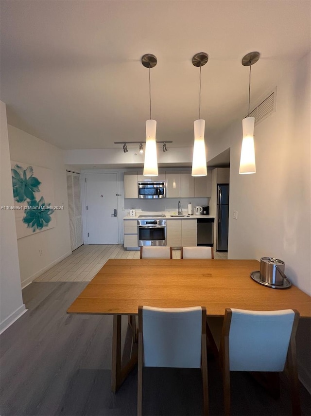 kitchen with stainless steel appliances, hanging light fixtures, and hardwood / wood-style floors