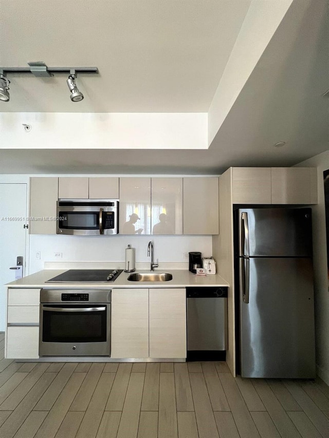 kitchen with stainless steel appliances, light wood-type flooring, and sink