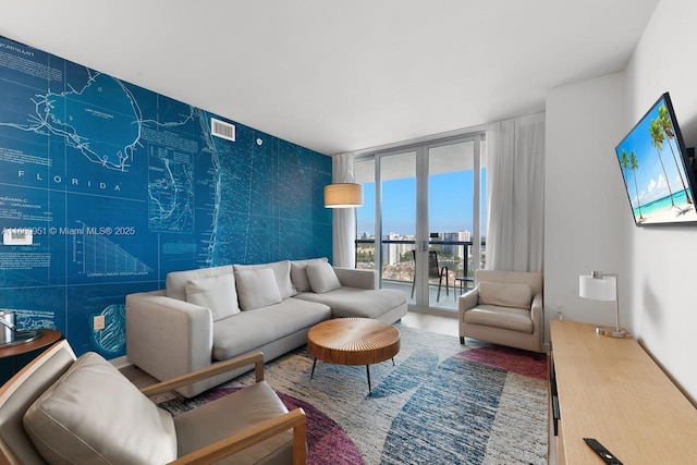 living room featuring a wall of windows, visible vents, and wood finished floors