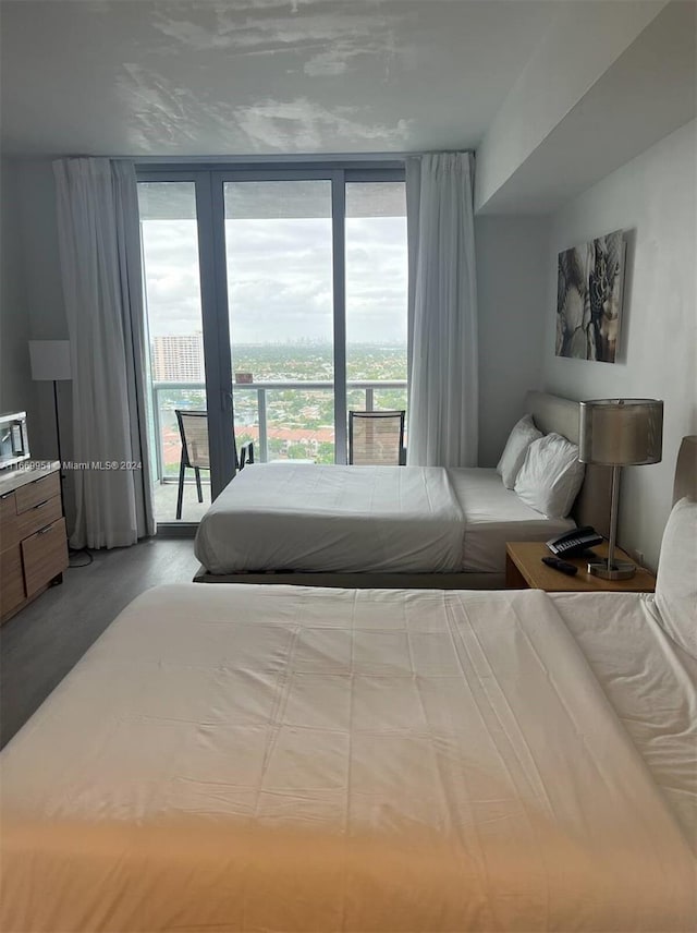 bedroom featuring expansive windows, light wood-type flooring, access to exterior, and multiple windows