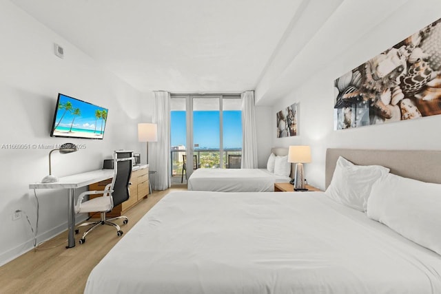 bedroom featuring access to outside, light wood finished floors, baseboards, and expansive windows