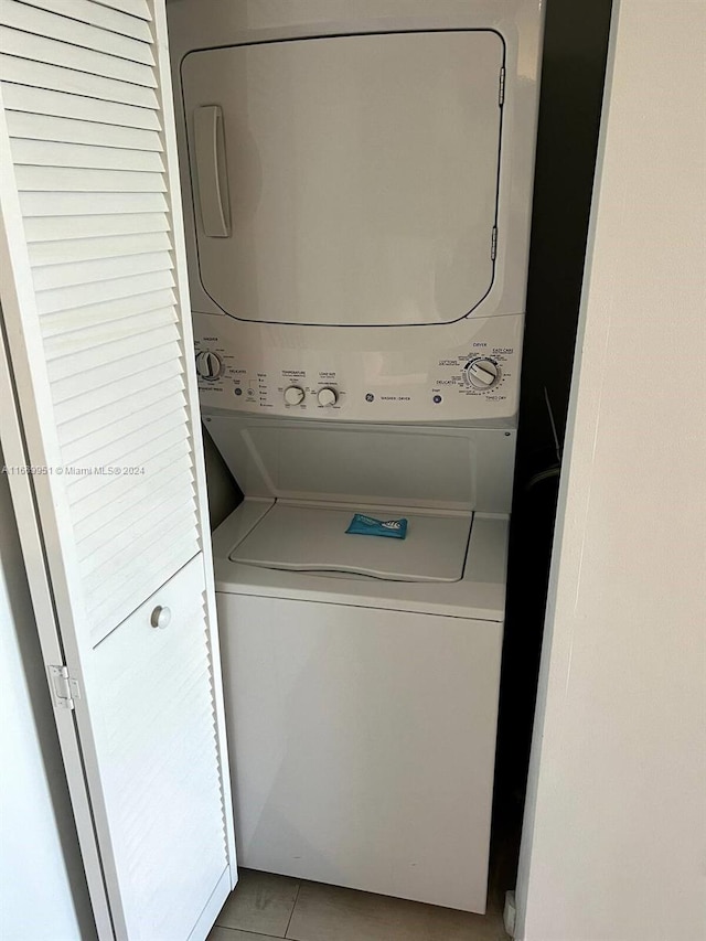 clothes washing area featuring stacked washer / dryer and light tile patterned flooring