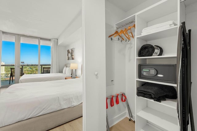 bedroom with a wall of windows, access to exterior, and wood finished floors