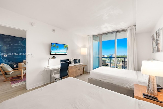 bedroom with baseboards, a wall of windows, light wood-style floors, and access to outside