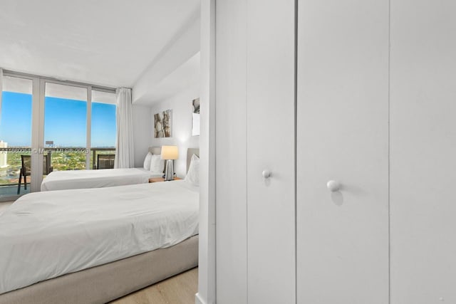 bedroom featuring access to outside, wood finished floors, and expansive windows