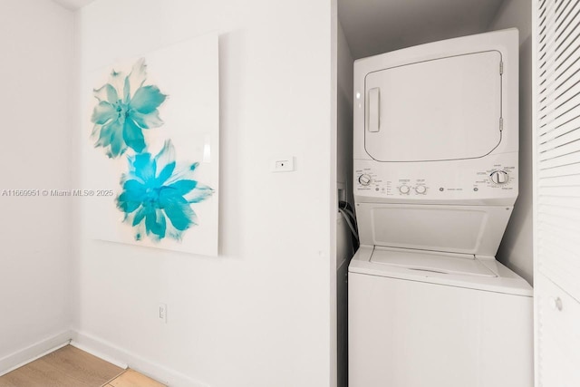 laundry room with laundry area, stacked washer / drying machine, and baseboards