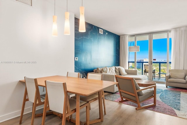 dining area with visible vents, wood finished floors, baseboards, and expansive windows