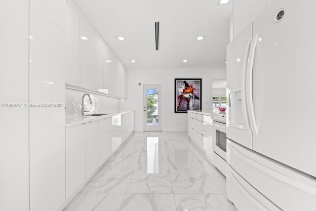 kitchen with sink, white appliances, and white cabinetry