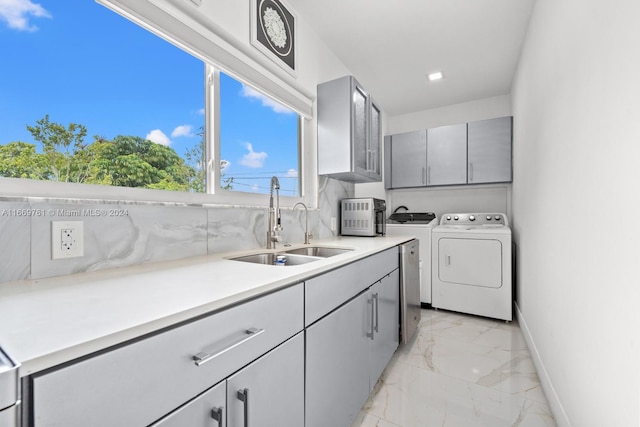 clothes washing area with sink, washer and dryer, and cabinets