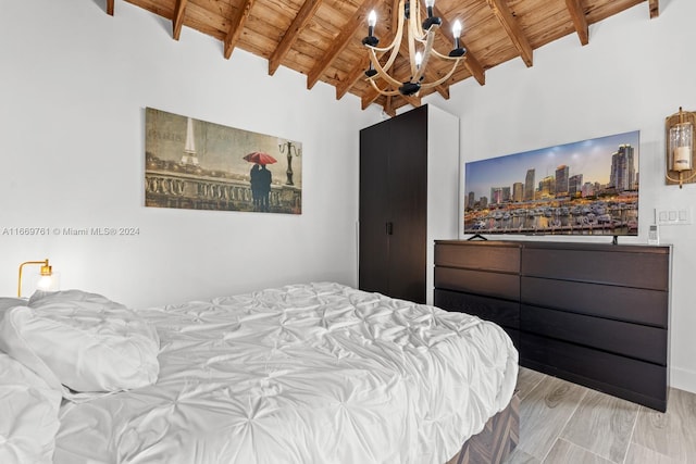 bedroom with an inviting chandelier, light wood-type flooring, vaulted ceiling with beams, and wooden ceiling