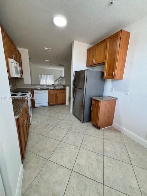 kitchen with light tile patterned floors, sink, and white appliances