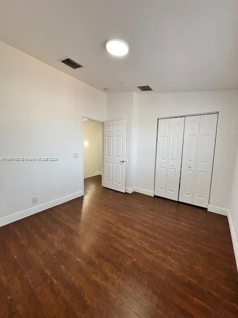 unfurnished bedroom with a closet and dark wood-type flooring