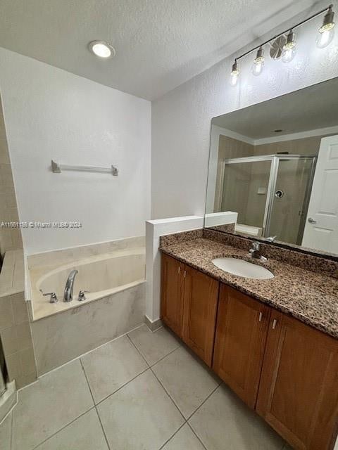 bathroom featuring tile patterned flooring, a textured ceiling, independent shower and bath, and vanity