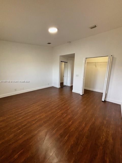 unfurnished bedroom with a closet and dark hardwood / wood-style flooring