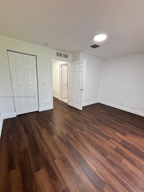 unfurnished bedroom with dark hardwood / wood-style flooring and a closet