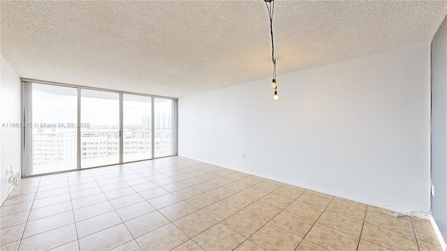 tiled spare room featuring a textured ceiling, expansive windows, and a wealth of natural light