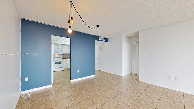 unfurnished room featuring a textured ceiling and light tile patterned floors