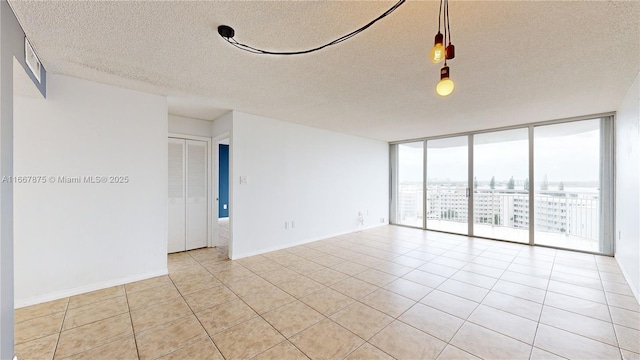 unfurnished room featuring a textured ceiling, light tile patterned floors, and floor to ceiling windows