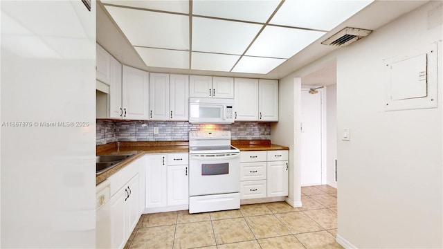 kitchen with white cabinets, tasteful backsplash, electric panel, light tile patterned floors, and white appliances