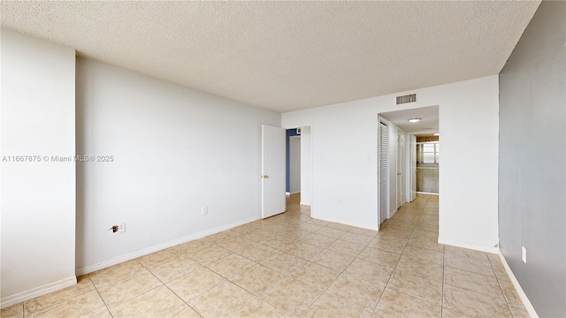 tiled spare room featuring a textured ceiling