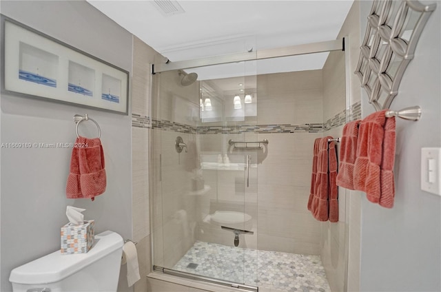 bathroom featuring a shower with shower door and toilet