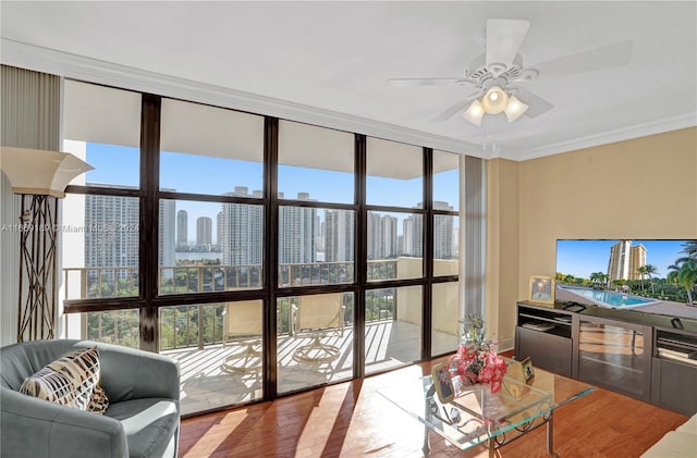 living room with a wealth of natural light, expansive windows, hardwood / wood-style floors, and crown molding