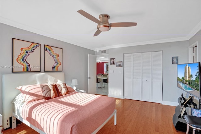 bedroom with ceiling fan, a closet, light wood-type flooring, and ornamental molding