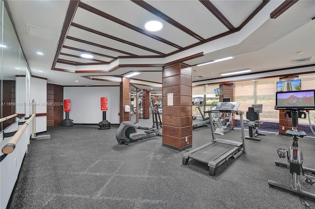 exercise room with ornamental molding, a tray ceiling, and ornate columns