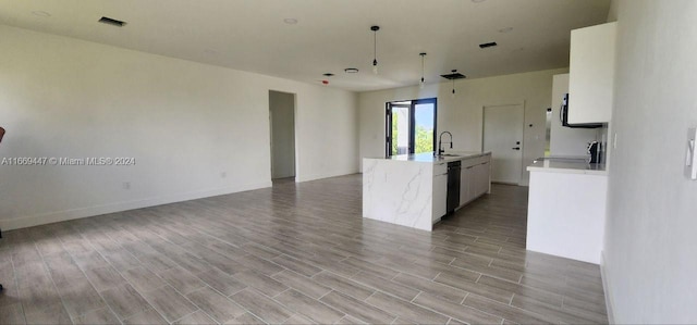 kitchen with white cabinets, sink, a center island with sink, light hardwood / wood-style flooring, and decorative light fixtures