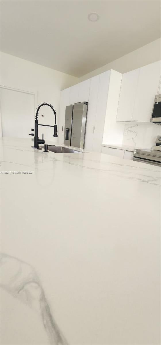 interior details with stainless steel range oven, white cabinetry, and sink