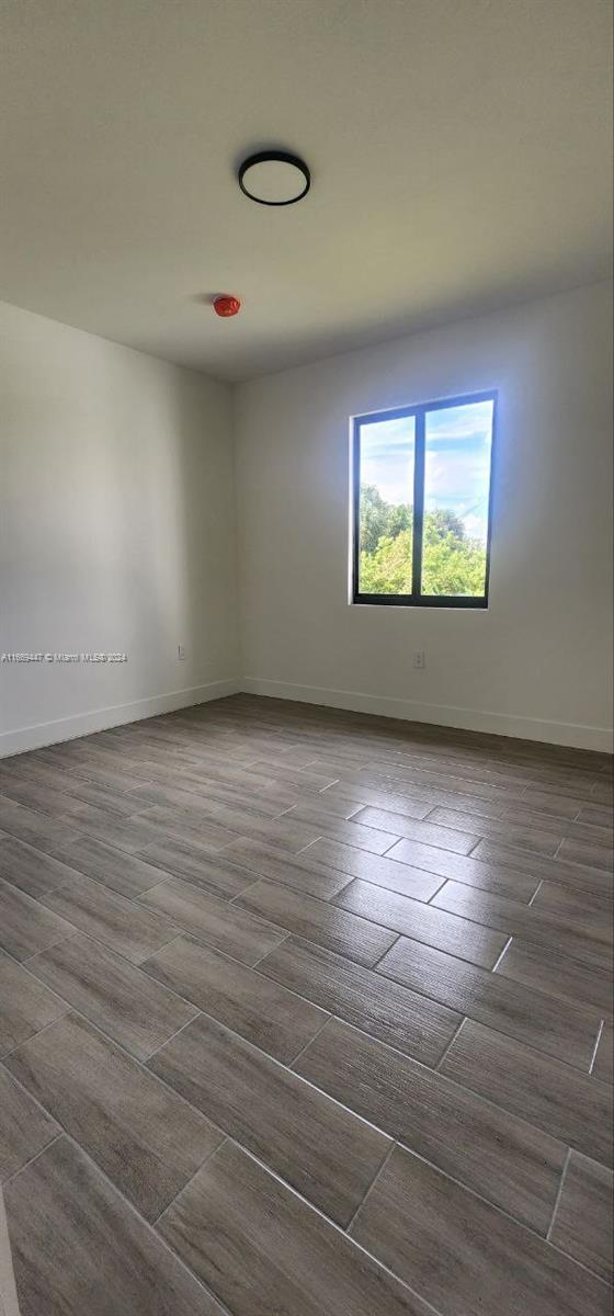 empty room with dark hardwood / wood-style flooring