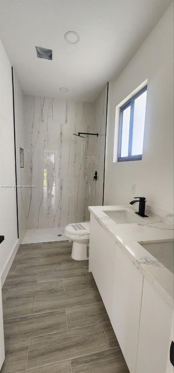 bathroom with vanity, a tile shower, toilet, and hardwood / wood-style flooring