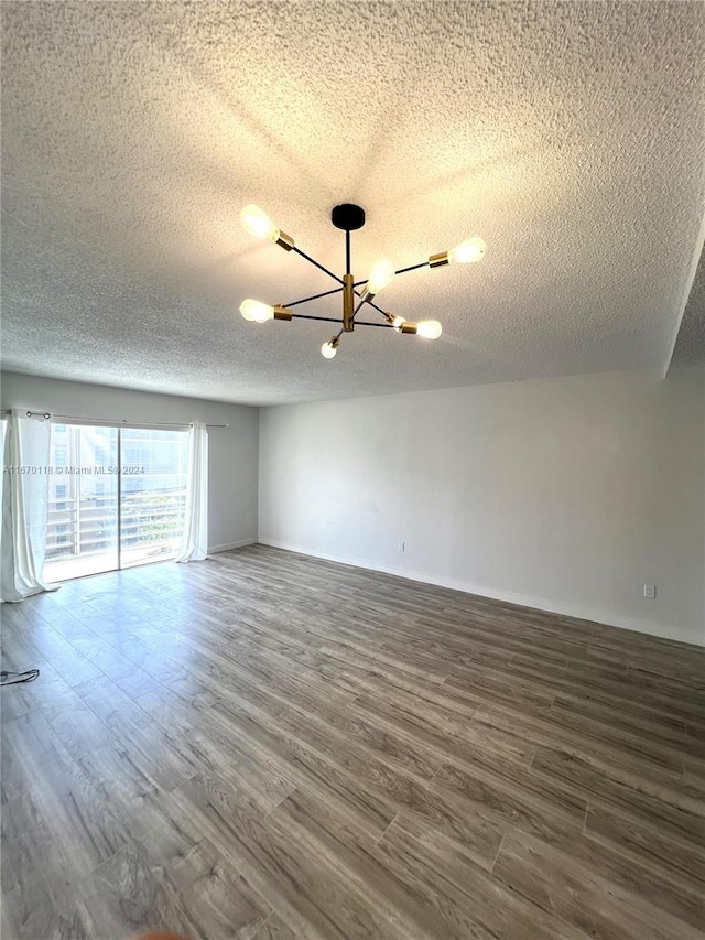 empty room featuring a textured ceiling, a chandelier, and hardwood / wood-style flooring