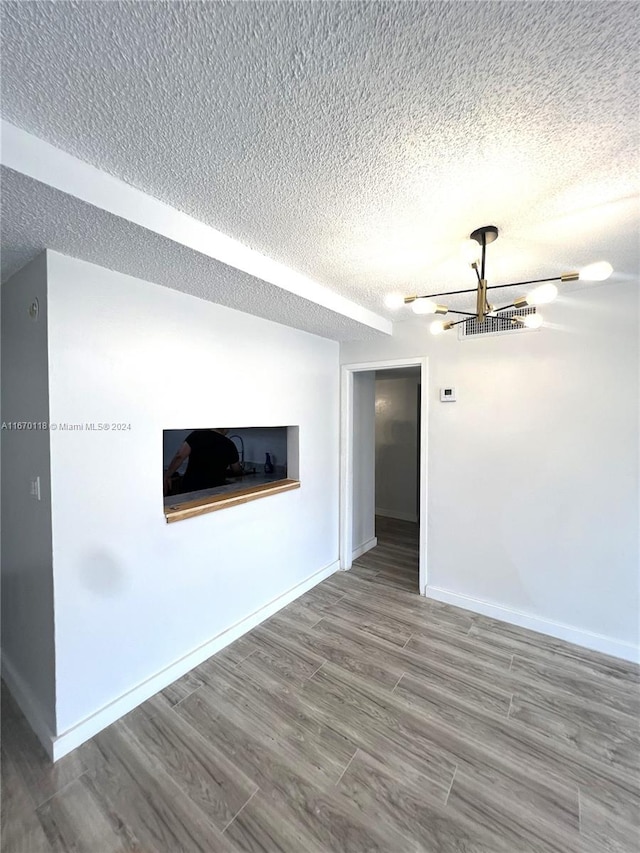 unfurnished living room with wood-type flooring and a textured ceiling