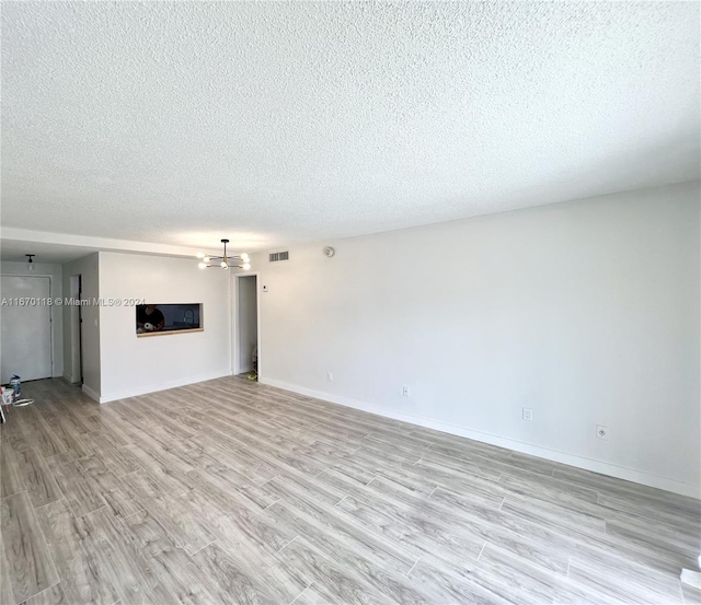 unfurnished living room featuring a textured ceiling and light hardwood / wood-style flooring