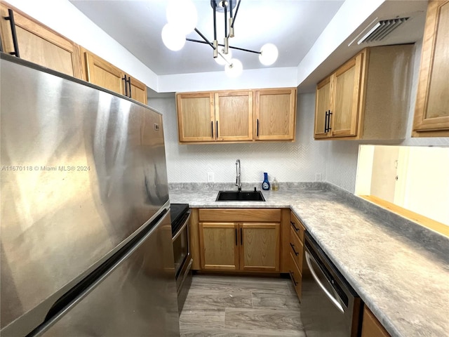 kitchen with appliances with stainless steel finishes, sink, dark wood-type flooring, and a notable chandelier